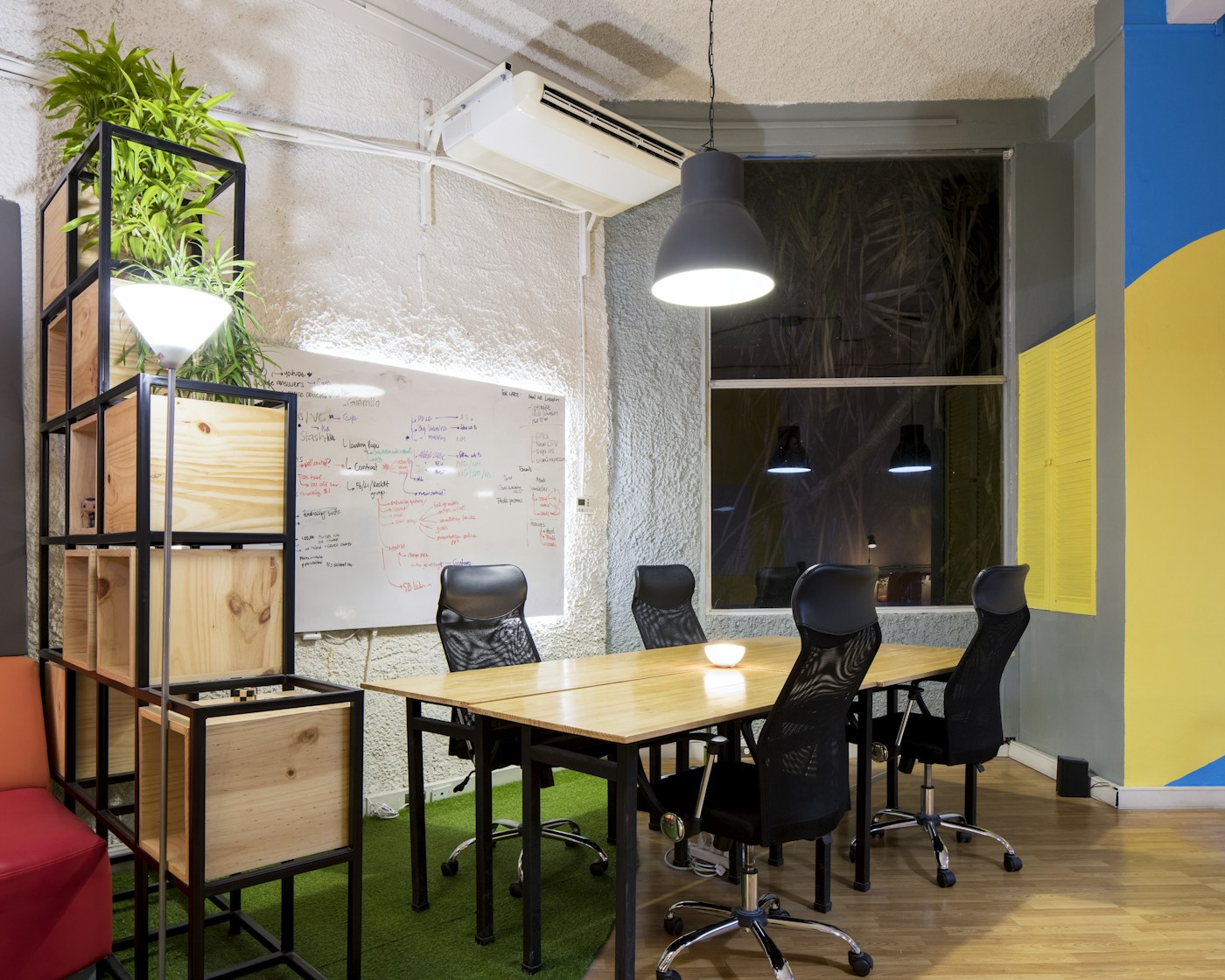A shared workspace with a whiteboard, pendant lighting and plants